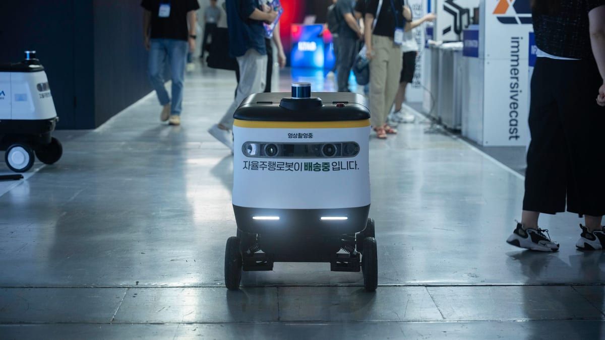 Delivery robot moving through a busy indoor corridor